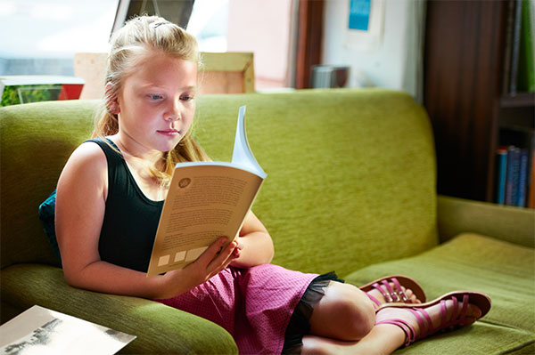 girl reading book on couch